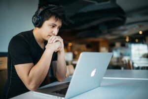 man wearing headphones while sitting on chair chatting to friends