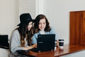 two woman sitting near table using laptop child safety online